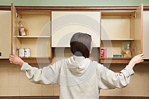 Woman Looking In Empty Food Cupboards photo
