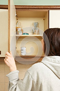 Woman Looking In Empty Food Cupboards photo