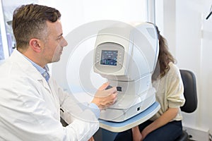 Woman looking at eye test machine in ophthalmology clinic