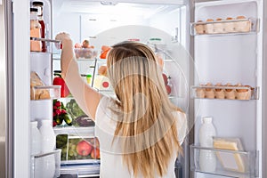 Woman Looking At Food In Refrigerator