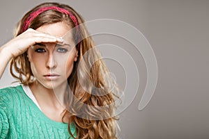 Woman looking forward and having put her palm to forehead