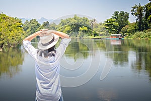 Woman looking forward to river with put her hands on head and she has feeling relax and happiness.