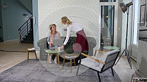 Woman Looking At Friend Using Mobile Phone In Cafe