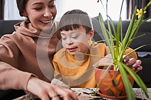 Woman looking at green plants and smiling while spending time at home with her son