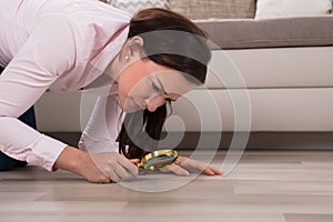 Woman Looking At Hardwood Floor Through Magnifying Glass