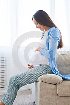 Woman looking at her belly on the sofa