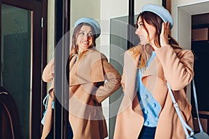 Woman looking at her reflection in mirror. Stylish girl trying spring clothes on by wardrobe at home. Beauty fashion