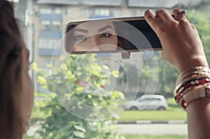 Woman looking at her reflection in the rearview