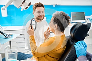 Woman looking at her tooth in the mirror, satisfied with hygienic teeth cleaning