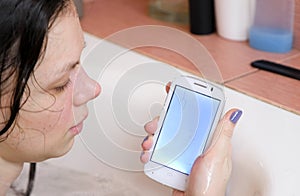 Woman is looking on her wet phone in bathroom.