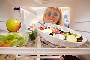 Woman Looking Inside Fridge Full Of Food And Choosing Salad