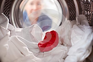 Woman Looking Inside Washing Machine With Red Sock Mixed With White Laundry