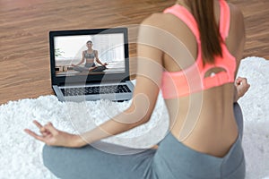 woman looking laptop practice yoga lotus pose online course at home