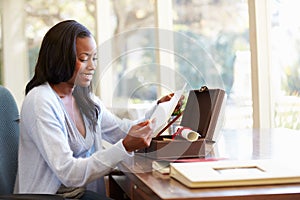 Woman Looking At Letter In Keepsake Box On Desk