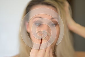 Woman looking at a loose tuft of hair in consternation