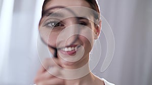 Woman Looking Through Magnifier And Smiling Close Up