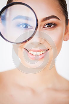 Woman Looking Through Magnifier And Smiling Close Up