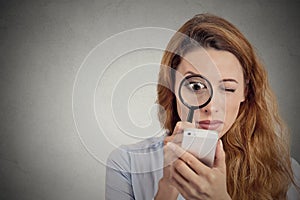 Woman looking through magnifying glass on smart phone screen