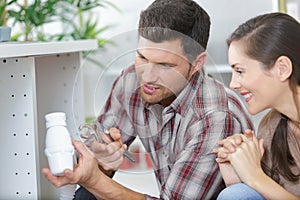 woman looking at male plumber repairing sink pipe in kitchen