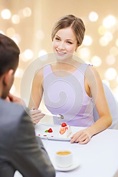 Woman looking at man and eating cake at restaurant