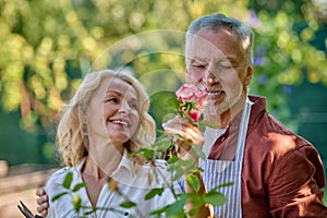 Woman looking at man enjoying scent of flower