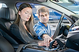 Woman Looking At Mechanic Checking Gearshift Of Car