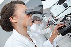 woman looking through microscope in lab
