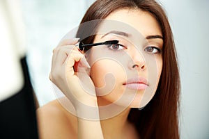 Woman looking at mirror while doing makeup