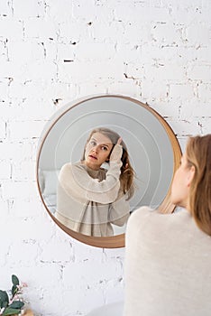 Woman looking at the mirror, making up in the morning