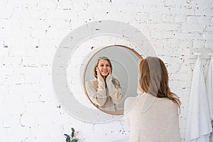 Woman looking at the mirror, making up in the morning