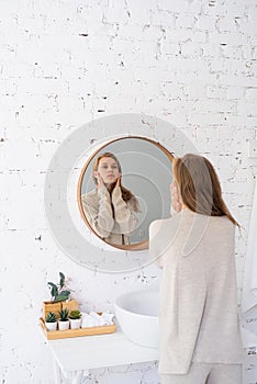 Woman looking at the mirror, making up in the morning