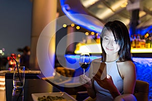 Woman looking at mobile phone at bar