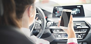Woman looking at mobile phone while driving a car. Driver using smart phone in car.