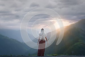Woman looking out at the mountains with sky above
