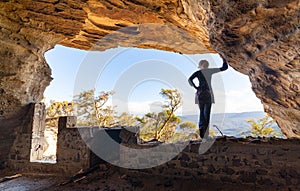 Woman looking out to mountain views from a cave