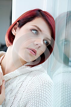 Woman looking out window with sad expression