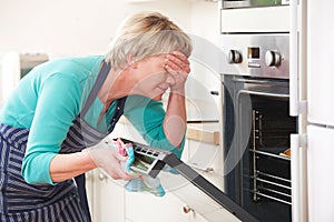 Woman Looking In Oven And Covering Eyes Over Disastrous Meal