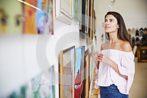 Woman Looking At Paintings In Art Gallery