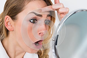 Woman looking at pimple in mirror