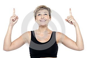 Woman looking and pointing upwards with both hands