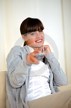 Woman looking and pointing at you with remote