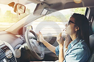 Woman looking in rear view mirror and making up in car
