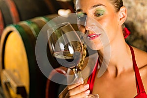 Woman looking at red wine glass in cellar