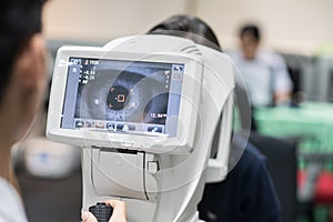 Woman looking at refractometer eye test machine in ophthalmology