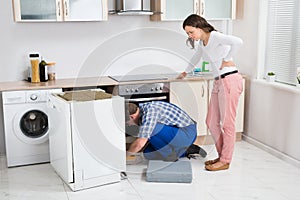 Woman Looking At The Repairman Repairing Dishwasher
