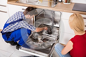 Woman Looking At Repairman Repairing Dishwasher