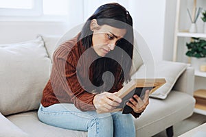 Woman looking sadly at the picture frames in her hands, crying over memories, state of depression and loss of a person