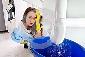 Woman Looking At Sink Pipe Leakage In Kitchen