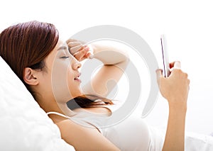 woman looking smart phone with tired eyes on the bed