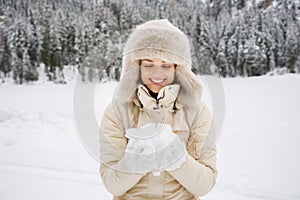 Woman looking on snow in hands while standing outdoors